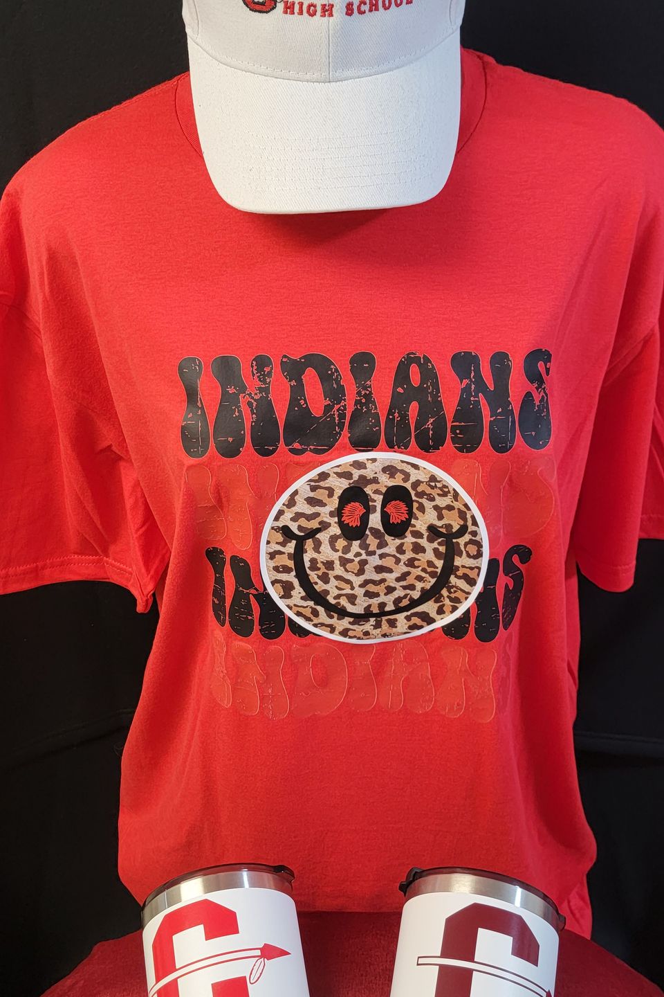 Example of Direct to Film (DTF) transfer - Cleveland Indians HS logo on a red t-shirt, embroidered logo cap, and tumblers. 
