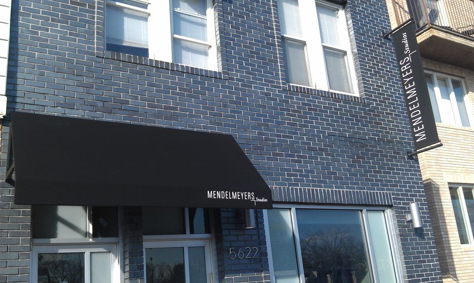 Black shed awning with white lettering and a matching projecting sign.
