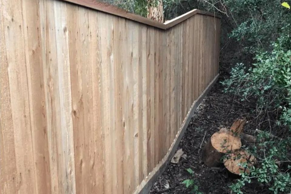 Custom wood fence construction along wooded property line