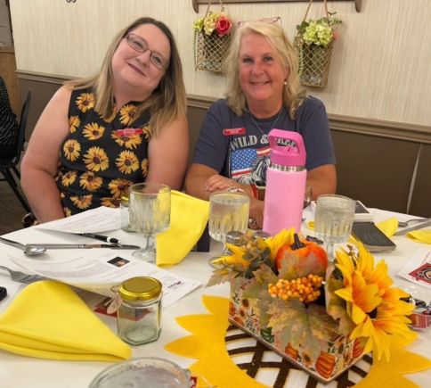 Two women attending the Mahoning Valley September meeting at a decorated table with fall-themed centerpieces.