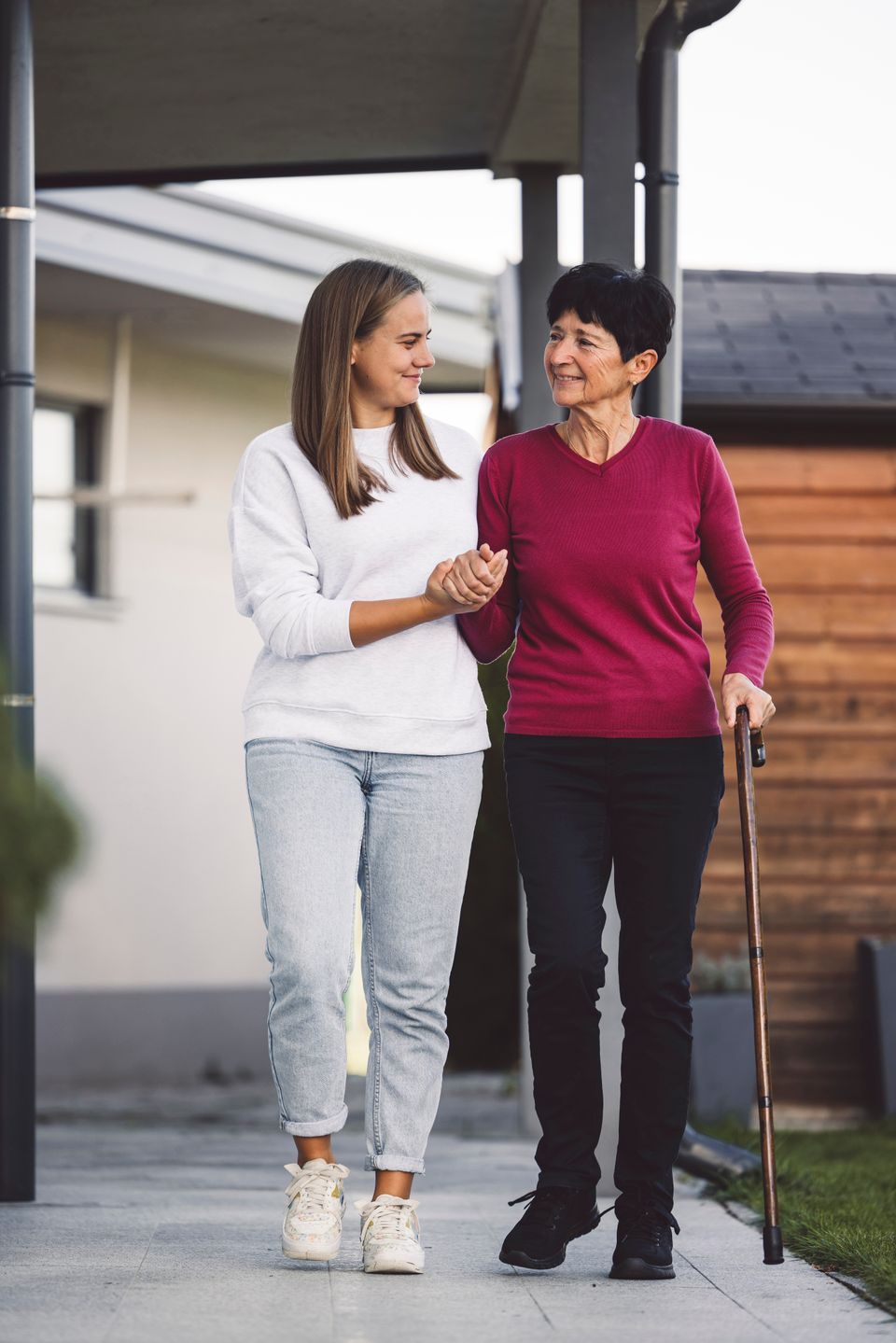 Nurse helping a senior women with every day chores, helping her to walk and move around the house