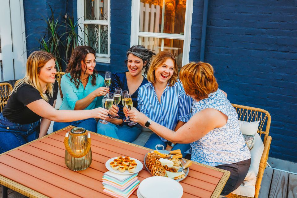 Friends relaxing together on a deck, laughing and enjoying glasses of Heavy Branch Cider.