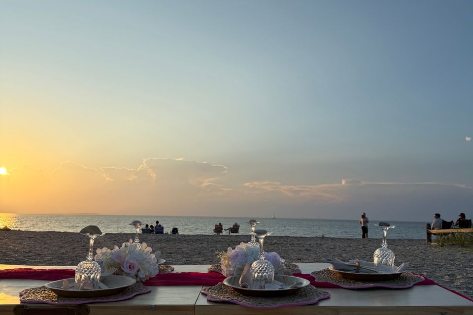 Sunset beach picnic styled with florals, glassware, and floor cushions along the Hamptons NY shore
