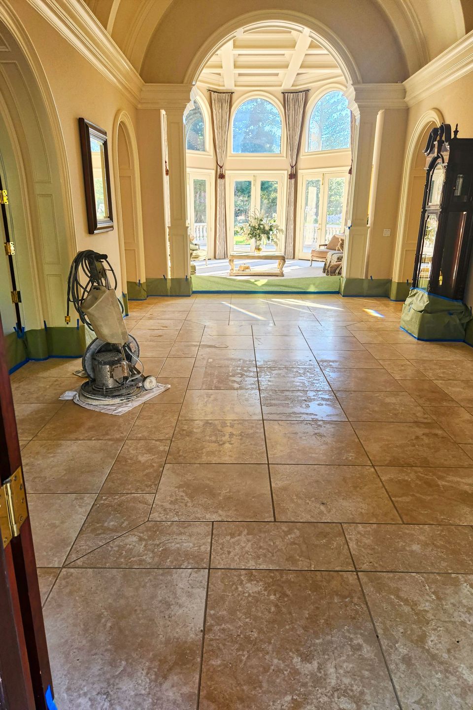 Elegant home interior with large tile floors, arched doorways, and floor‑cleaning machine set up for professional maintenance work