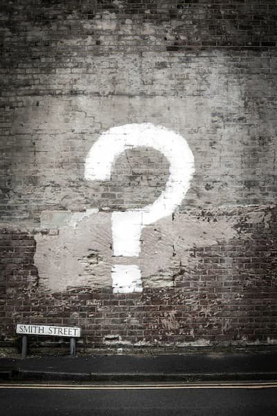 Question mark painted in white on a brick wall 