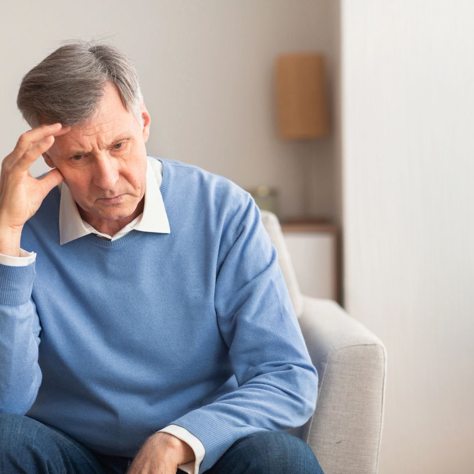 Sad Elderly Man Thinking About Loneliness Sitting On Couch At Home