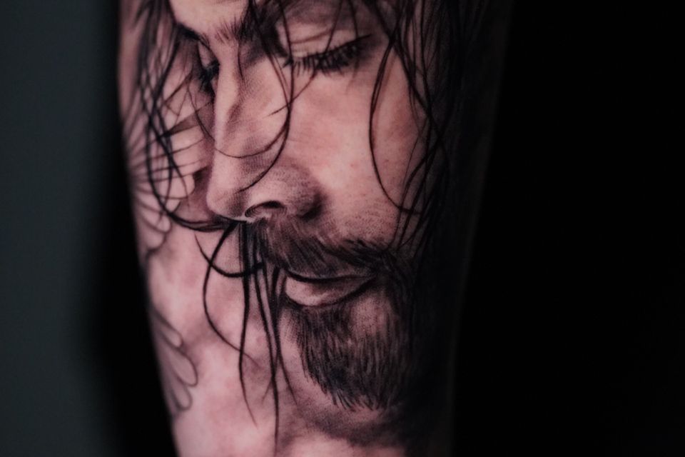 Image of an arm tattoo of Jesus with great detail of clouds and the crosses they were crucified