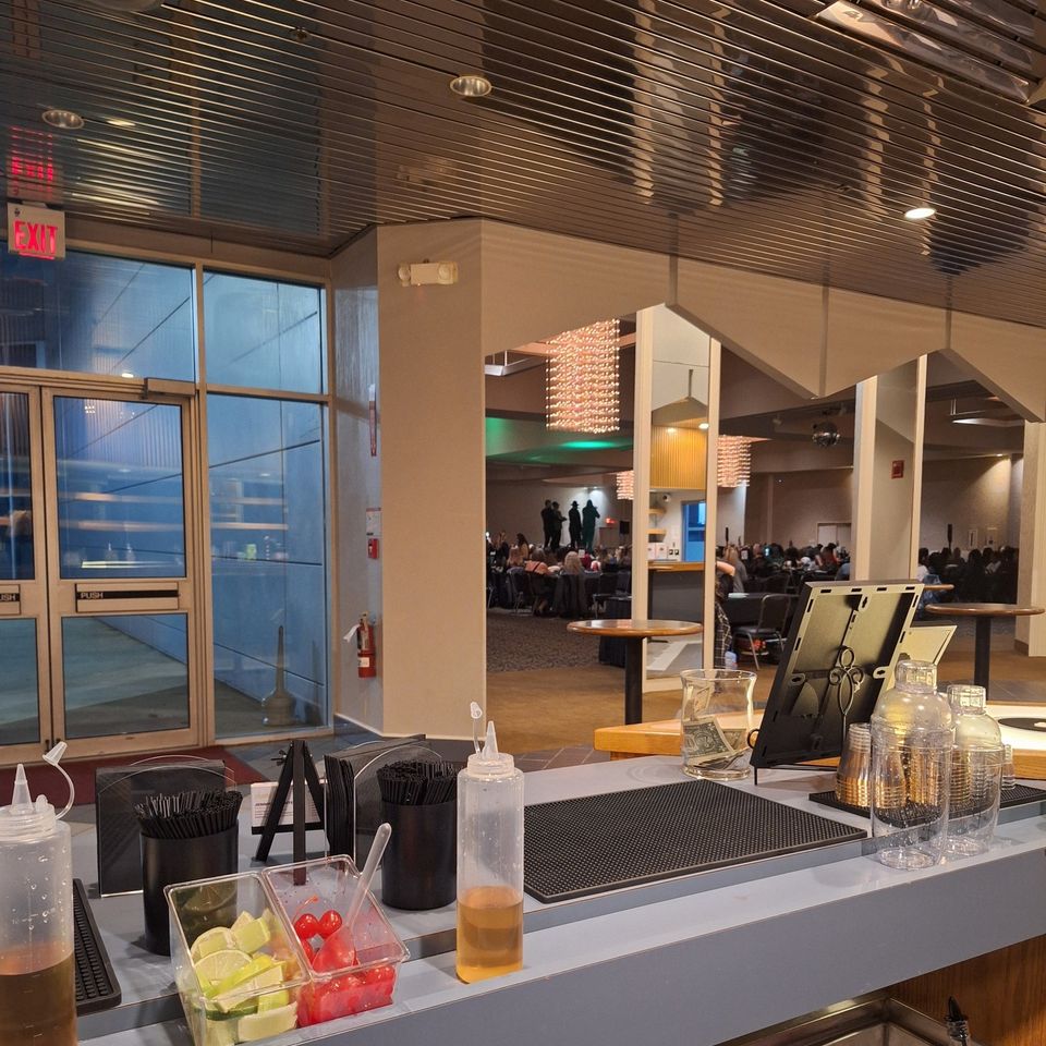 Long bar counter stocked with bottles, mixers, and service tools