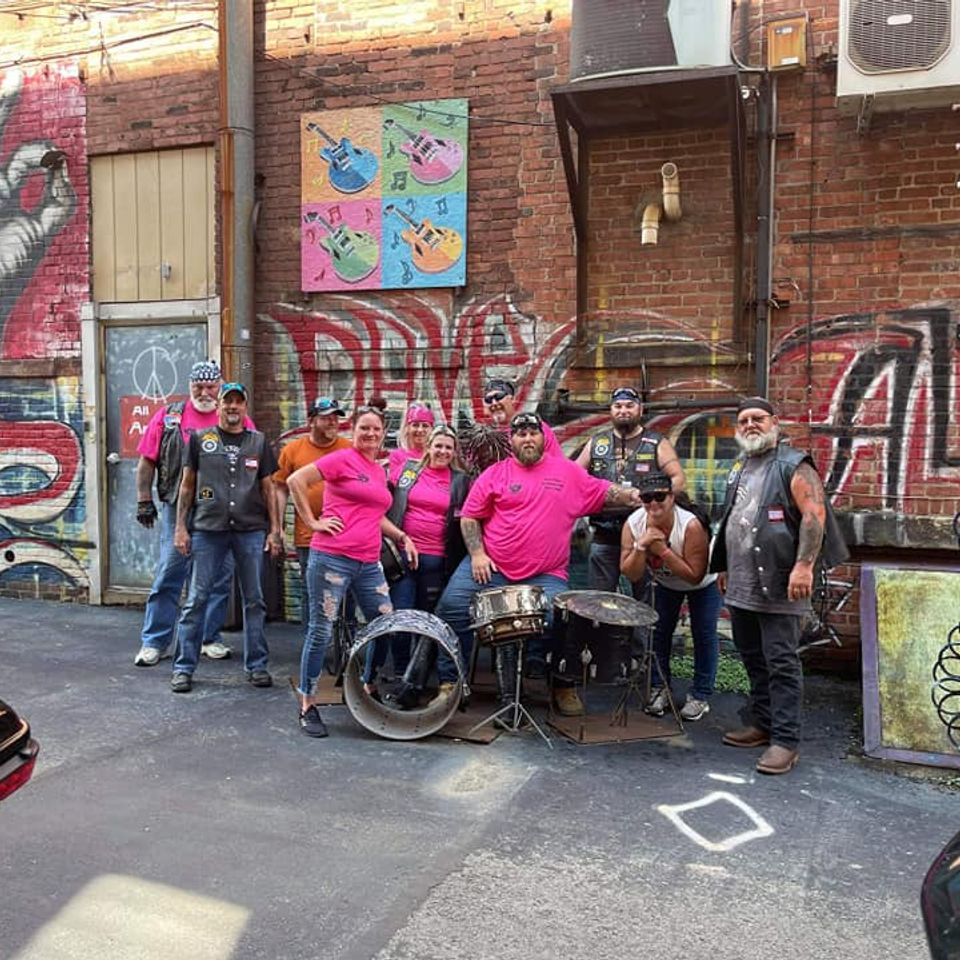 Heels N Wheels members and fellow riders posing together in an urban alleyway with colorful murals.
