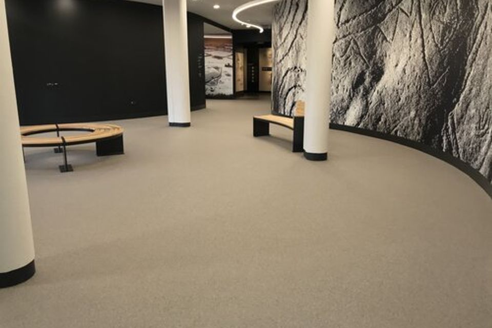 Commercial space with Quartz Carpet flooring, curved walls, and support columns.