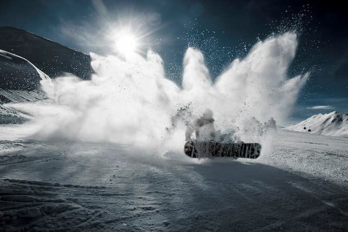 Snow splash as a snowboarder tries to stop down the mountain 