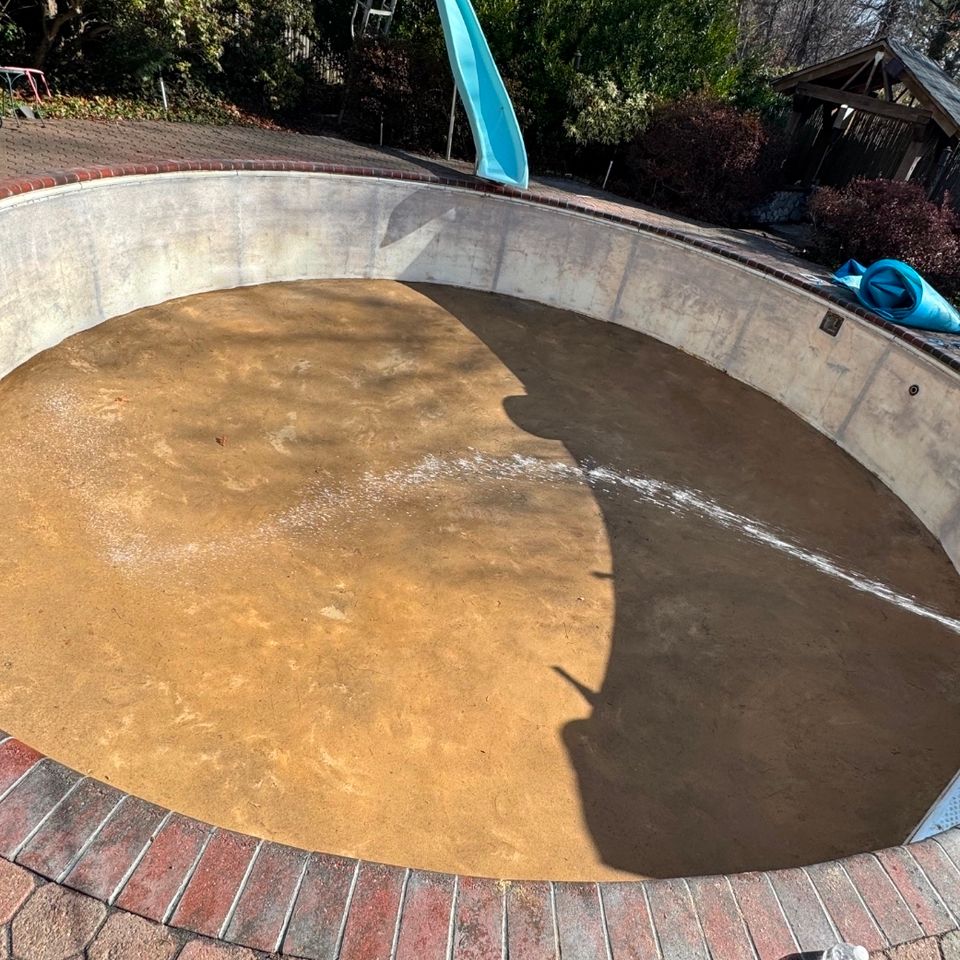 Drained kidney shaped pool with bare walls and floor prepped for a new liner