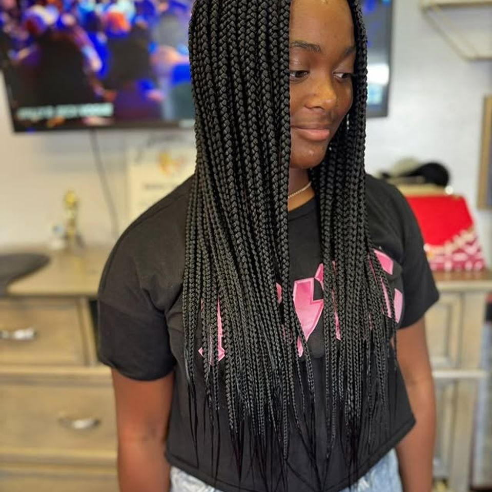 Long black knotless box braids styled on a smiling client in Los Angeles CA