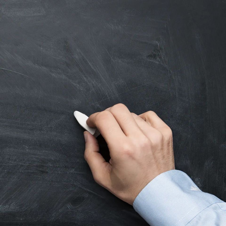 Close up of male hand writing on a blackboard with copy space for some text