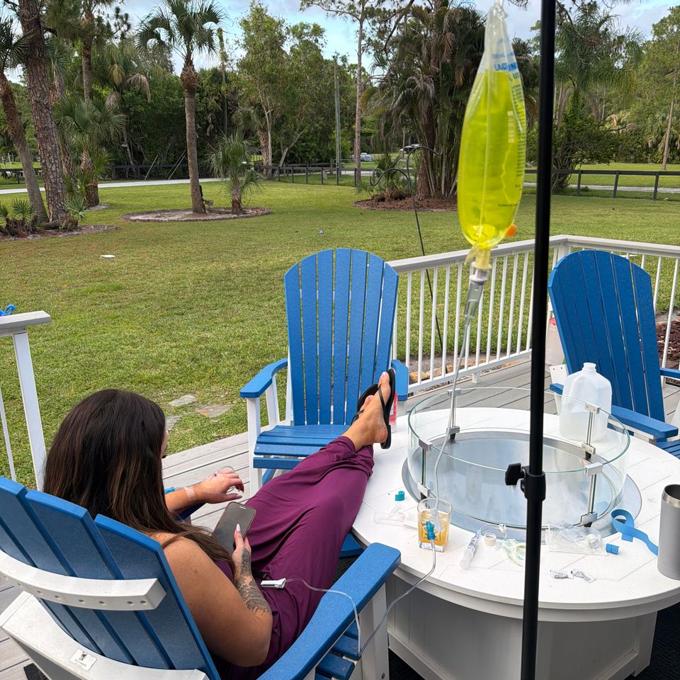 Woman receiving a mobile IV vitamin drip while relaxing on a backyard patio in Palm Beach County FL