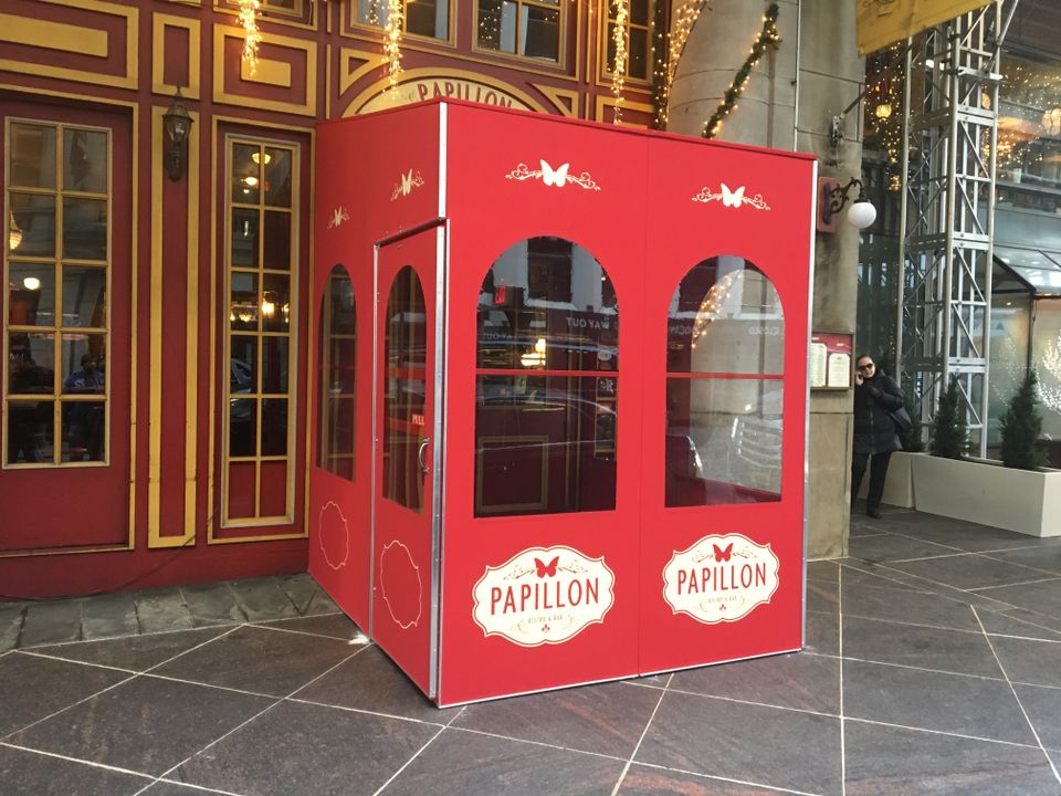 Red painted vestibule with arched windows and branded oval logo panels at an ornate building entrance