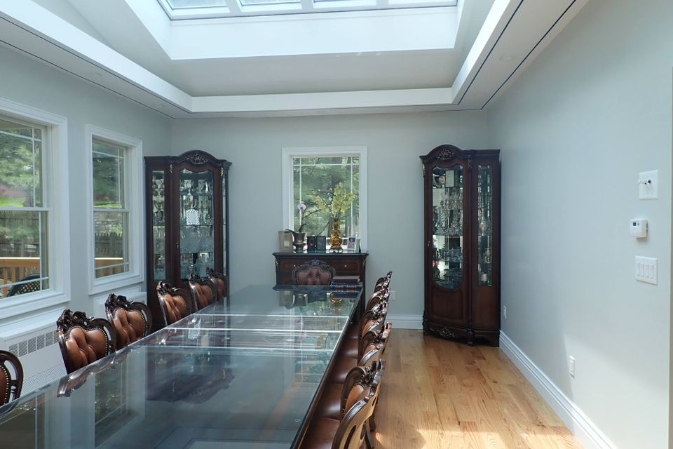 Luxury dining room with a skylight, large glass table, and classic furniture.