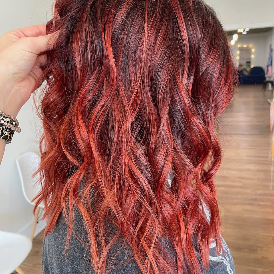 Medium wavy hair with bright red highlights over dark base after color service in Columbiana AL