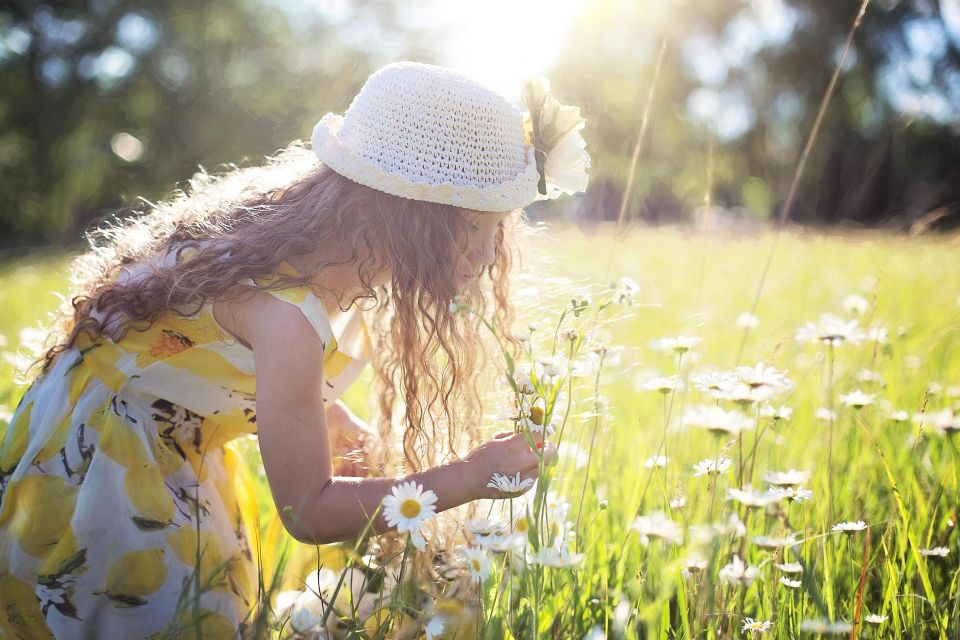 Woman smelling flowers outdoors, representing natural wellness and healthy lifestyle