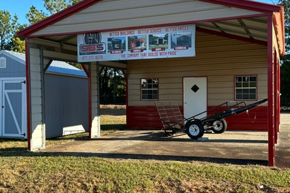Tan and red steel carport with SBSI banner and enclosed side room representing steel carports in Alabama