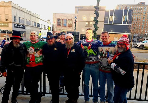Group of event attendees posing outdoors in downtown Youngstown wearing Christmas sweaters and holiday-themed accessories.