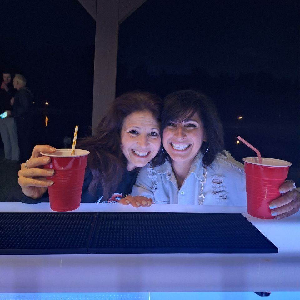  Two guests smiling and holding drinks at the full bar during a private party