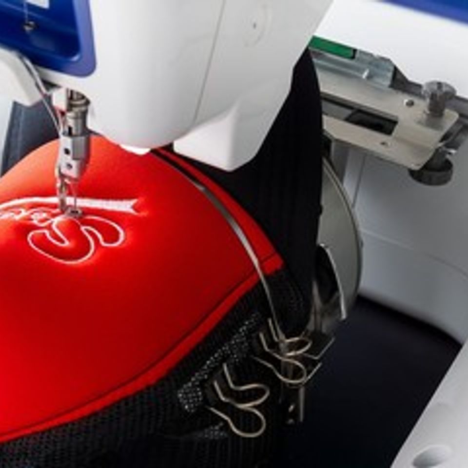 Embroidery machine sewing a design into a hat