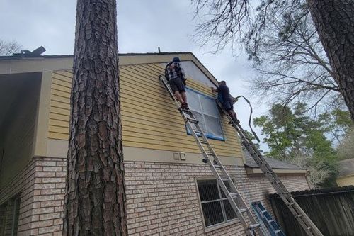Two painters prime second‑story siding from extension ladders in Cypress, TX