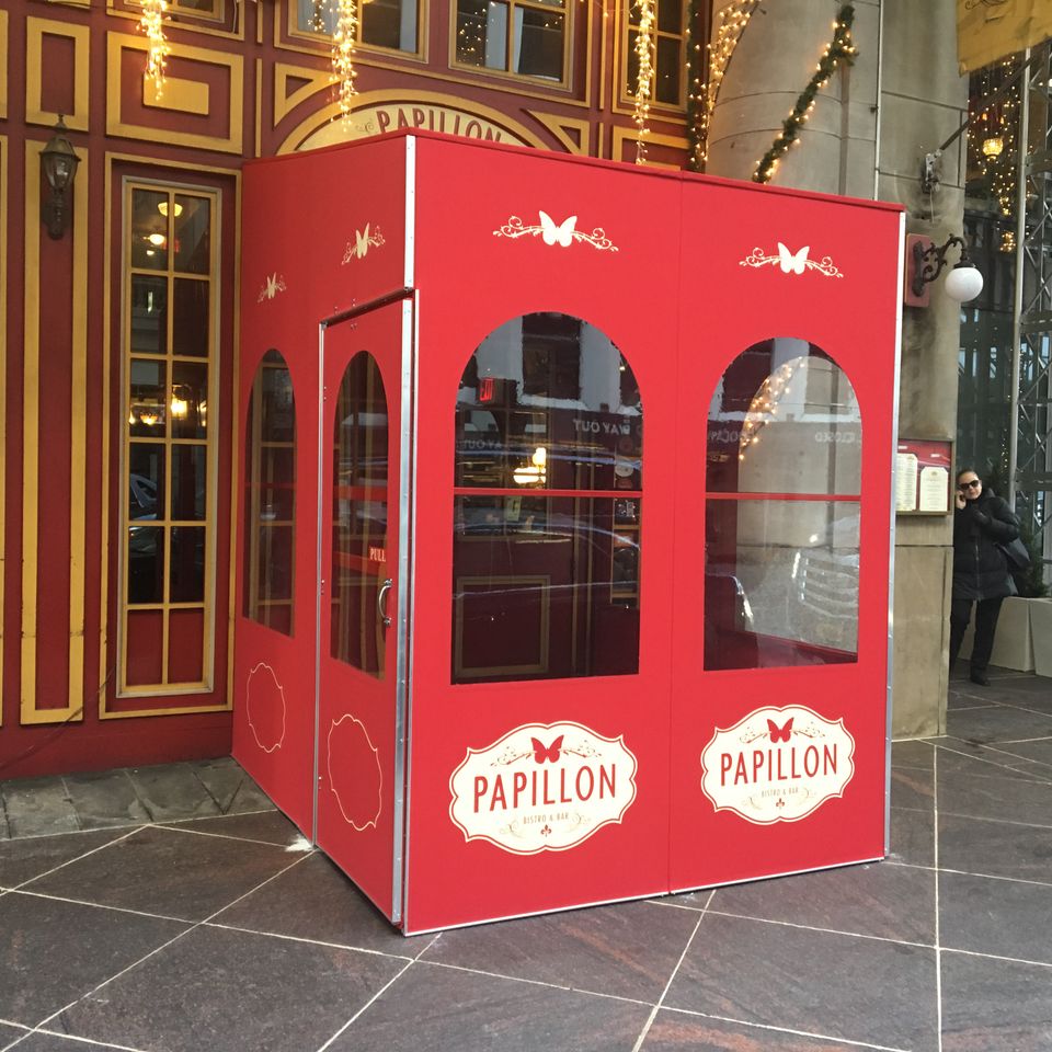 Red painted vestibule with arched windows and branded oval logo panels at an ornate building entrance