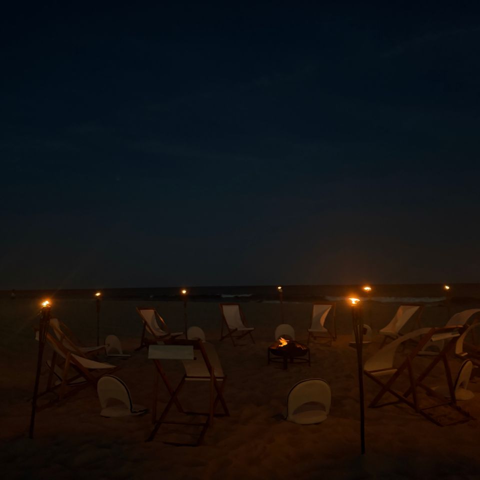 Beach fire pit surrounded by sling chairs and tiki torches at night on a Hamptons NY shoreline