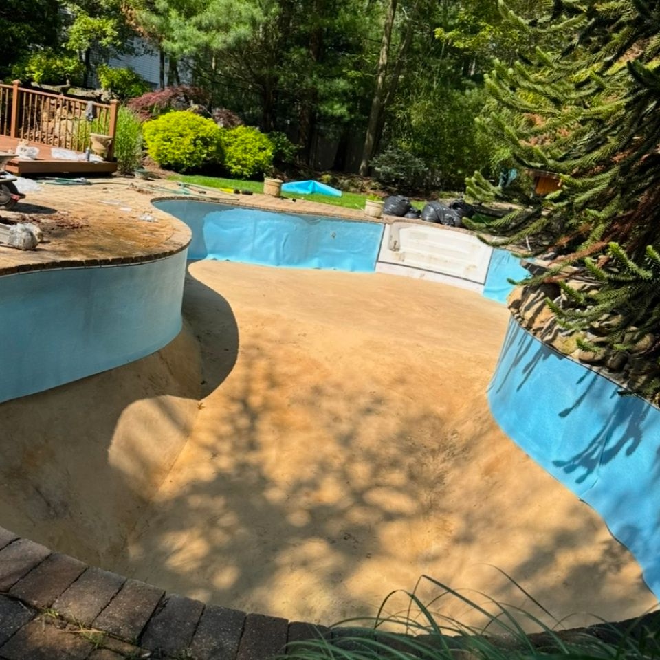 Empty inground pool with bare sand floor prepped for liner replacement in Long Island NY