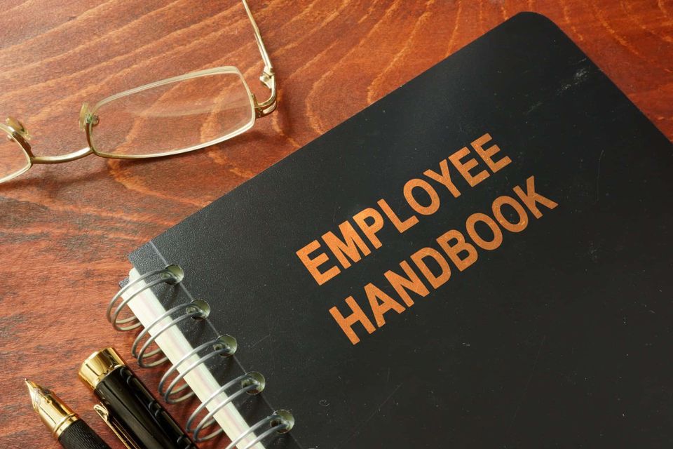 Employee handbook on a wooden table and glasses.