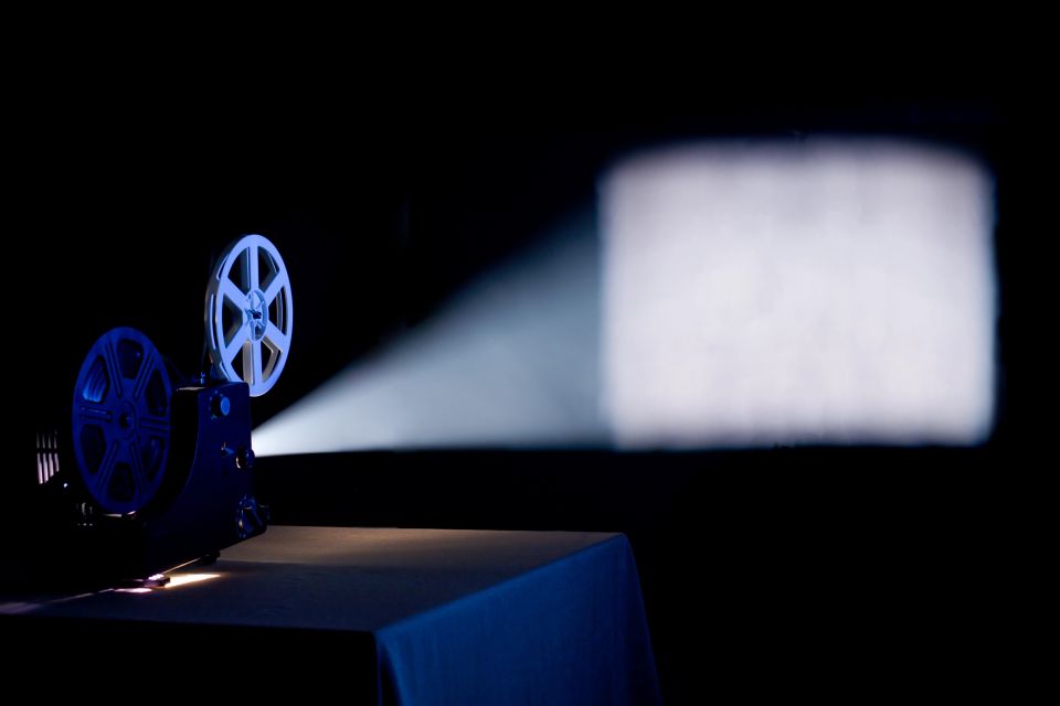 Old home film projector, running and projecting blank movie on a screen with visible beam of light