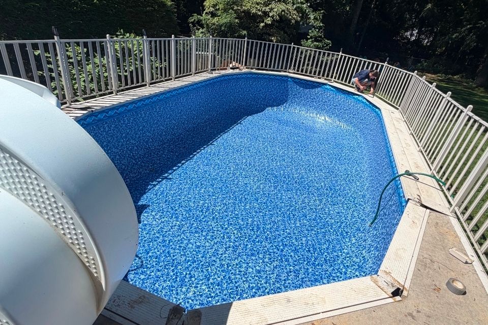 Oval above ground pool with new liner and surrounding safety fence after installation