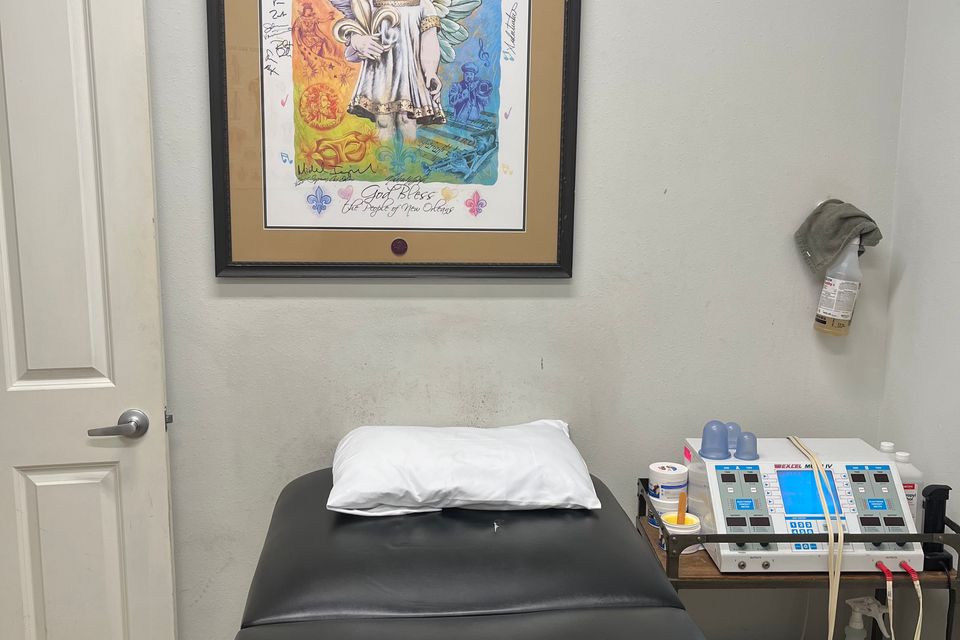 Therapy room at Mid City Physical Therapy in New Orleans, featuring a treatment table with a pillow, a medical device cart