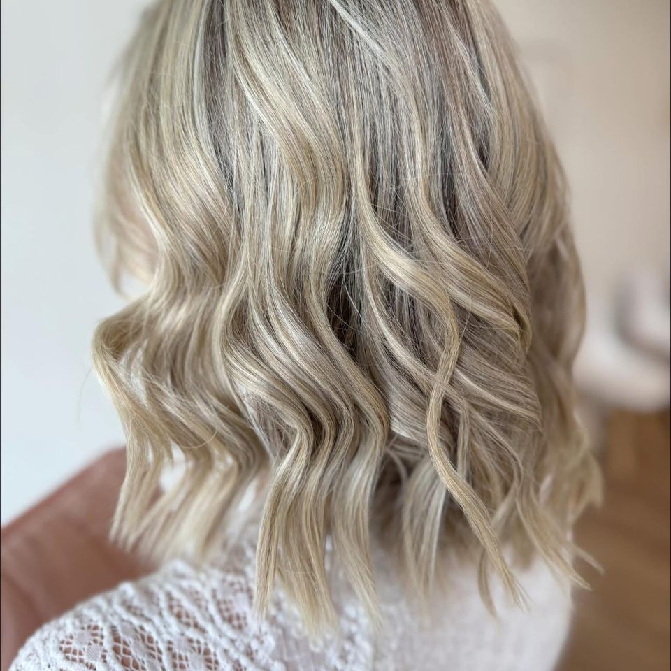 Medium wavy blonde hair with dimensional highlights after color and styling in Columbiana AL