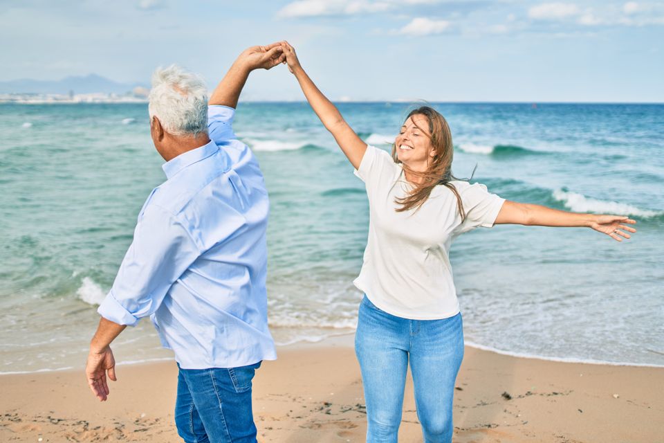 Middle age couple in love dancing at the beach happy and cheerful together