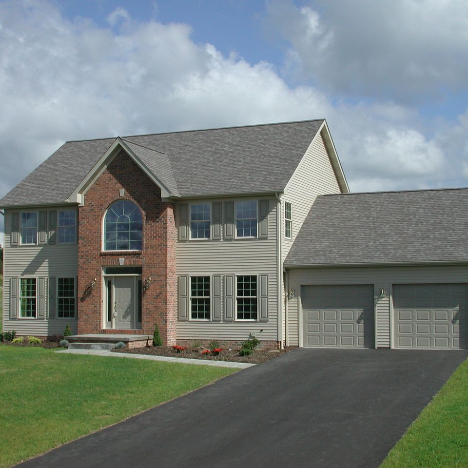 Two-story energy-performance home with a brick and siding exterior, attached three-car garage, and professionally landscaped front yard.