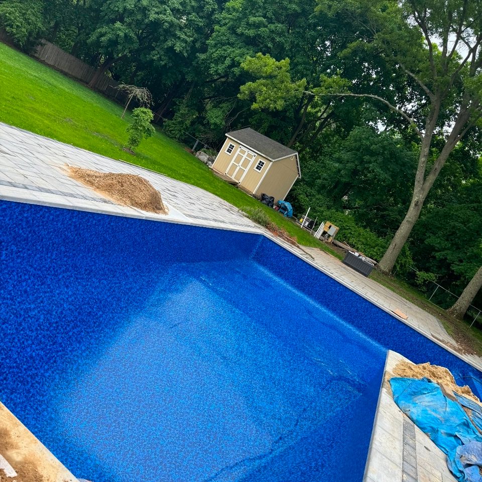 New vinyl liner installed in a backyard inground pool with paver deck and shed behind it