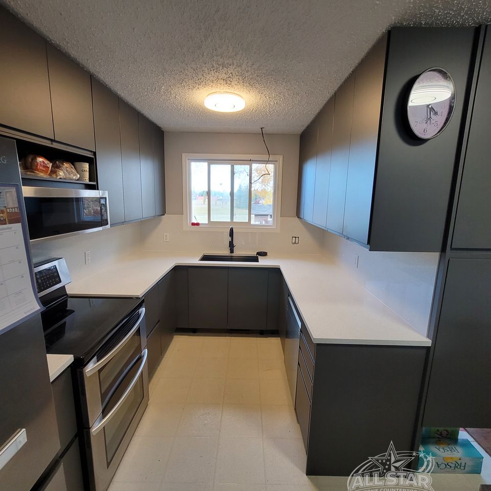 Galley kitchen with custom stone countertops and dark island in Houston, TX