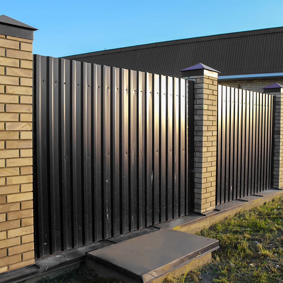 Professional installation of black metal fence with brick columns on concrete footing