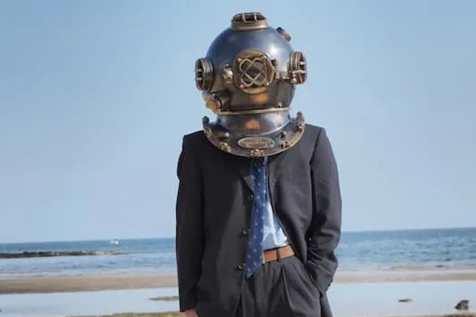 Man in business suit with old timey diver helmet on 
