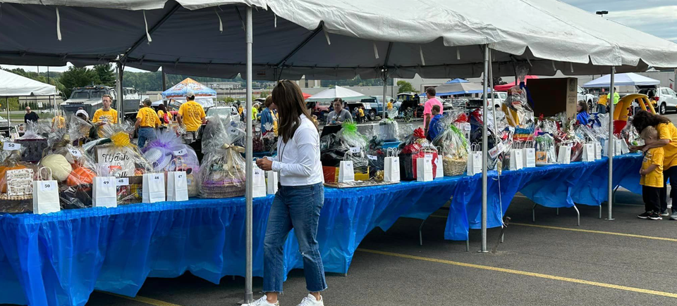 Tables filled with raffle baskets and prizes under a large tent during the DSAV Buddy Walk event.