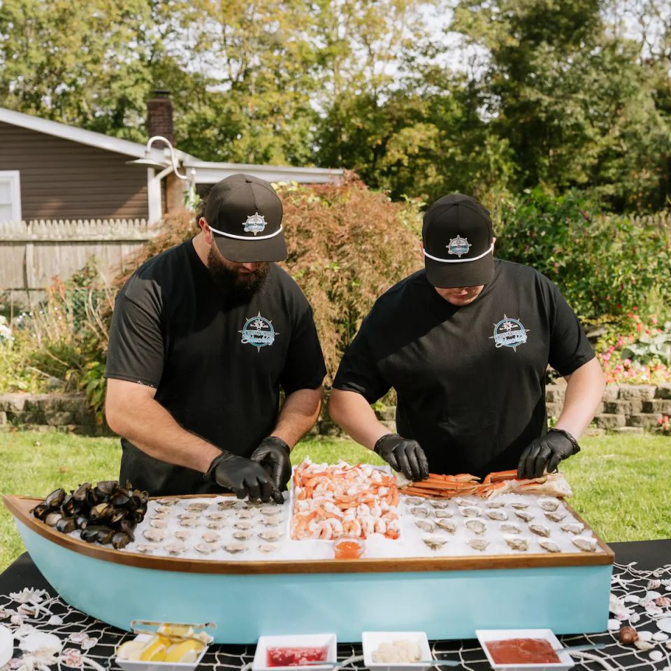 Sean and Mike, the owners of Shore2Shore Shucking working the raw bar, preparing food.