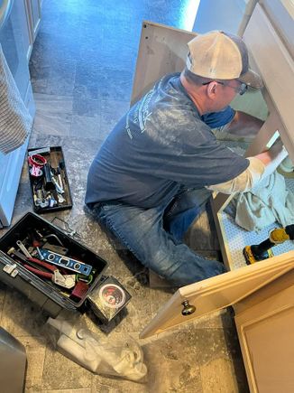 Kenny working under a sink for plumbing repair