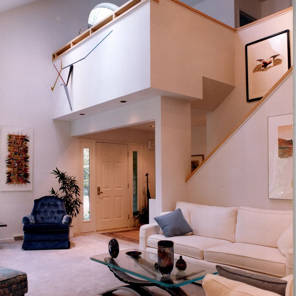 Remodeled living room featuring an open floor plan, high ceilings, a loft, staircase, modern furnishings, and abundant natural light.