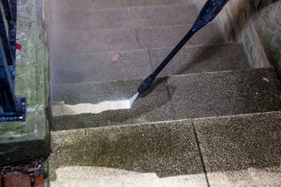 Pressure washing a concrete stairway to remove dirt, grime, and stains from the surface.