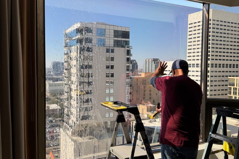 Willie Thomas installing commercial window tint on high-rise building in Sugar Land TX