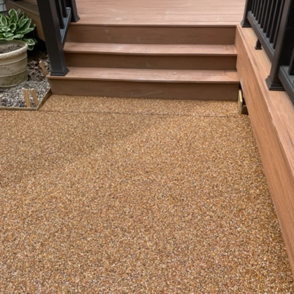 Outdoor patio with decorative flake epoxy flooring leading to composite deck stairs.