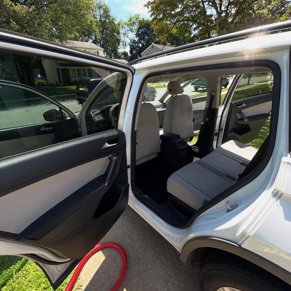 White Volkswagen Tiguan with rear door open showing freshly cleaned cloth seats during a Wilmington driveway interior detail